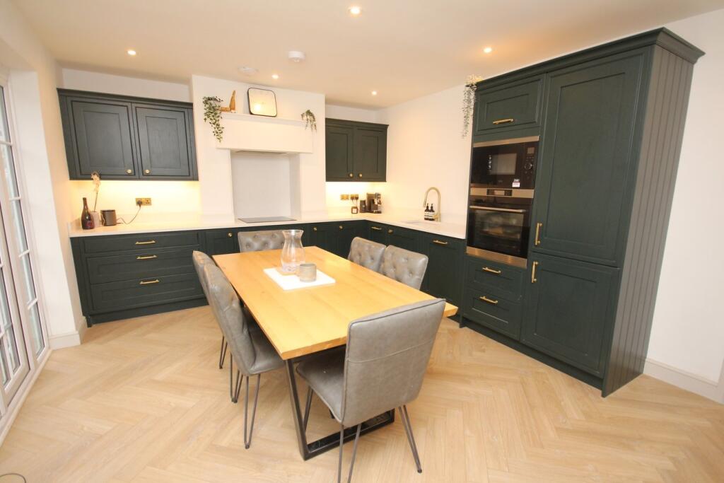 A heritage green shaker kitchen-diner with an oak dining table and a herringbone floor