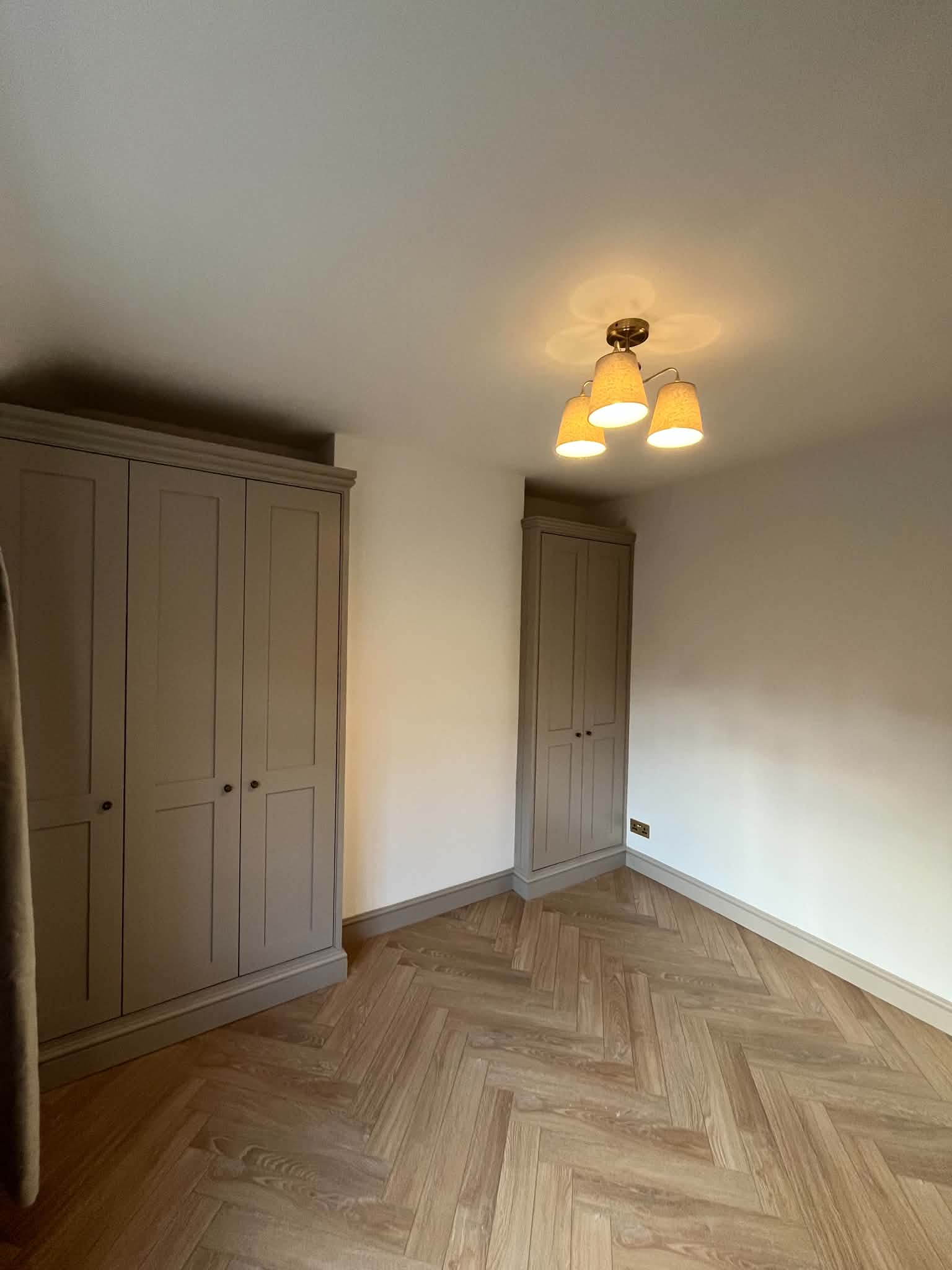 Painted shaker alcove wardrobes in a bedroom with a herringbone floor