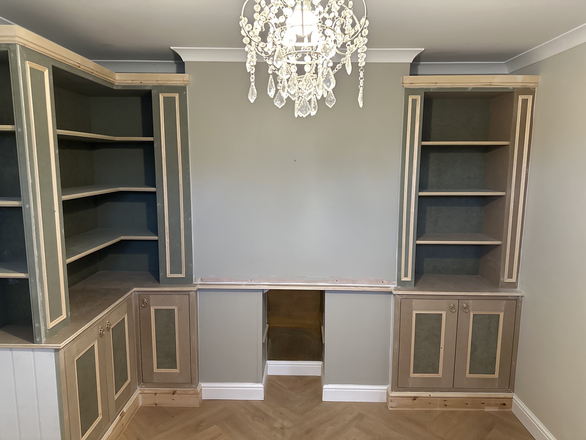 Alcove shelving and cupboards built either side of a desk recess, ready for decorating