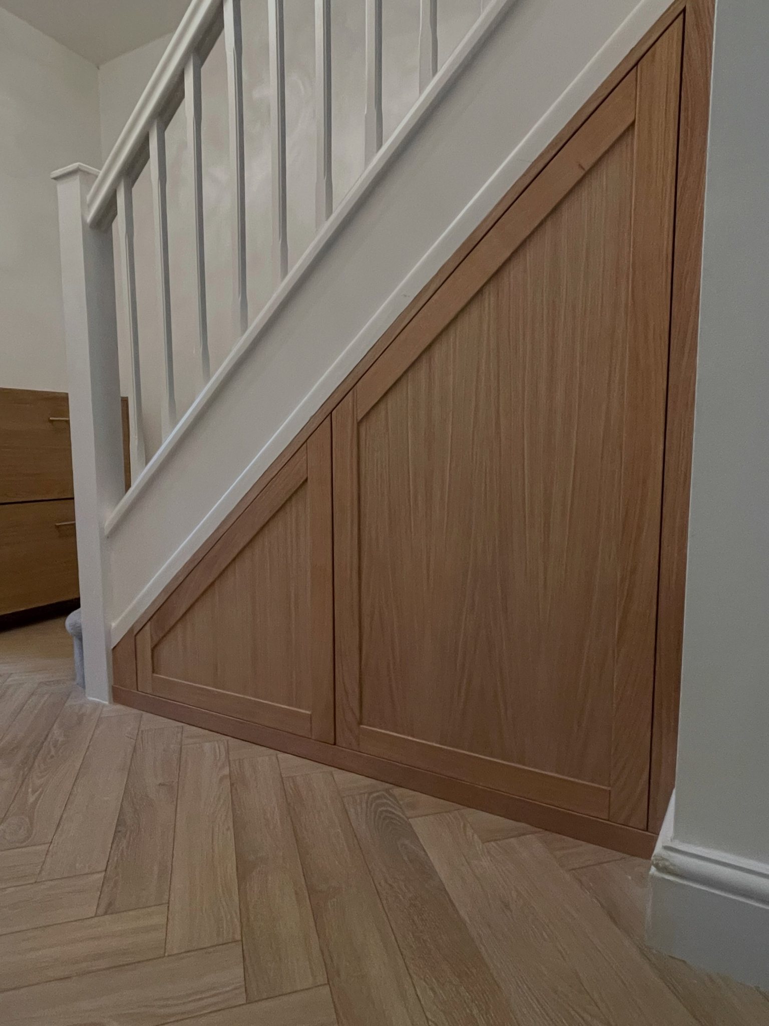Solid oak and oak veneer under-stairs storage with a handleless push-to-open door